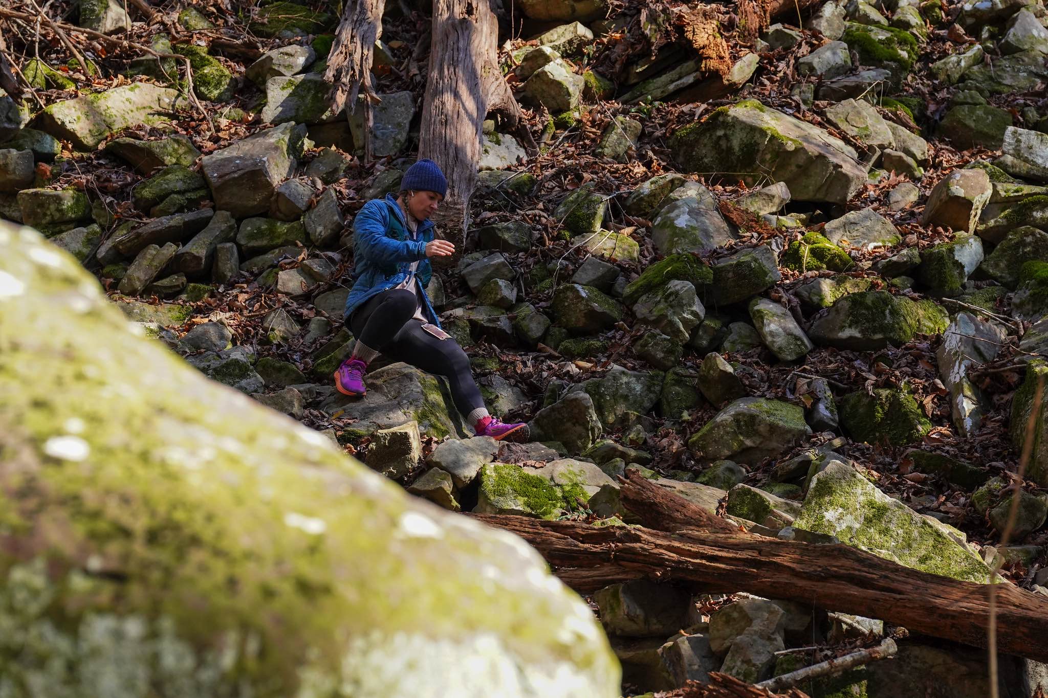 A runner descends a field of moss covered rocks