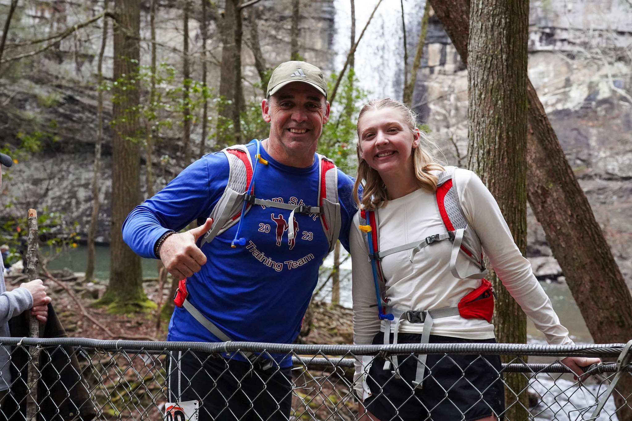 Two smiling finishers in front of the waterfall